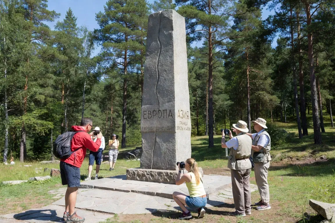 Stèle marquant la frontière Europe-Asie en Oural, touristes photographiant le monument